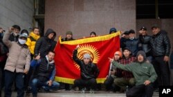 Protesters hold up a national flag at Kyrgyz government headquarters, in Bishkek, Kyrgyzstan, Oct. 6, 2020.