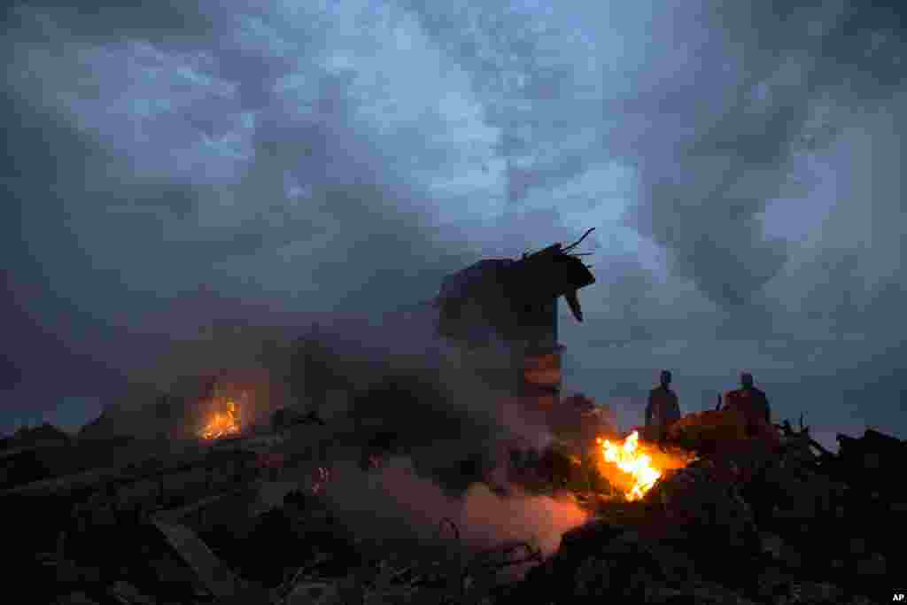 Orang-orang berjalan di antara reruntuhan pesawat penumpang yang jatuh di dekat desa Grabovo, Ukraina.