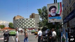 德黑兰市中心一个广场，行人在莱希的竞选旗帜下经过（2017年5月17日）
