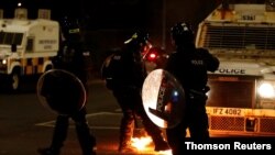 A police officer reacts next to fire during a protest in the Loyalist Tigers Bay Area of Belfast, Northern Ireland April 9, 2021.