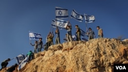 Children in the West Bank settlement of Itamar wave Israeli flags on a hilltop. (file) (VOA/Rebecca Collard)