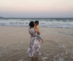 In this photo, Zou Xiaoqi, a single mother turned activist in Shanghai, holds her son as they visit a beach in Sanya, southern China's Hainan province in October, 2019. (Photo supplied by Zou Xiaoqi)