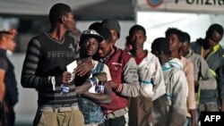 Les gens attendent de débarquer du navire de la garde côtière italienne "Diciotti" au port de Pozzallo, en Sicile le 19 juin 2018.