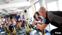 FILE- People are seen exercising in a spinning class. A new study claims short, intense exercise is as good as longer, moderate exercise.