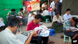 People read local newspapers at a roadside journal shop in Yangon, Myanmar, Nov. 11, 2015.