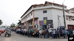 Des fonctionnaires forment une file d'attente devant la branche d’une banque à Abidjan pour percevoir leurs salaires, Côte d’Ivoire, 1er mars 2011.