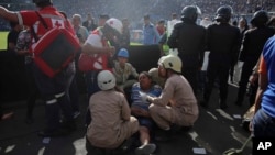 Un hombre herido es asistido después de una mortal estampida en el Estadio Nacional en Tegucigalpa, Honduras, el domingo, 28 de mayo de 2017.