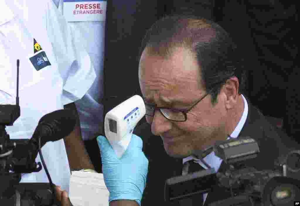 French President Francois Hollande gets his temperature taken as he arrives at the Donka hospital, Conakry, Guinea, Friday, Nov. 28, 2014.