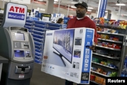 FILE - A shopper carries a Samsung television at a Best Buy store in Westbury, New York. Nov. 27, 2015.
