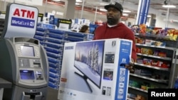 FILE - A shopper carries a Samsung television at a Best Buy store in Westbury, New York. Nov. 27, 2015. 
