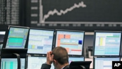 A trader reacts at his desk in front of the DAX board at the Frankfurt stock exchange, May 7, 2012.