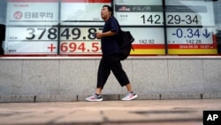 A person walks in front of an electronic stock board showing Japan's Nikkei index and Japanese Yen exchange rate at a securities firm Sept. 20, 2024, in Tokyo.