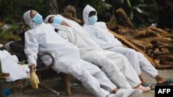 Petugas ambulans beristirahat di bangku setelah di tempat krematorium di Guwahati, India, pada 25 Juni 2021. (Foto: AFP/Biju Boro)