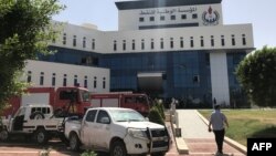 Firefighters and onlookers gather in front of the headquarters of Libya's National Oil Company in the capital Tripoli on September 10, 2018. Armed men stormed the building in Tripoli today where a blast and gunfire were heard, witnesses said.
