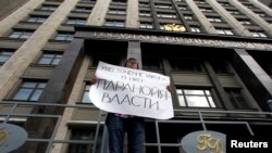 FILE - A lone activist protests restrictive law targeting foreign-funded NGOs working in Russia, outside the Duma, Russia's lower house of parliament, in Moscow.