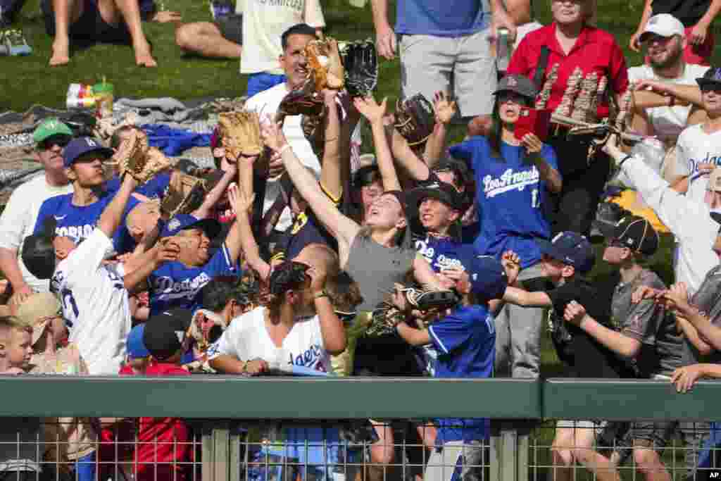 A fan catches a baseball thrown to them by Los Angeles Dodgers outfielder Tommy Edman (25) during a spring training baseball game against the Colorado Rockies, Feb. 27, 2025, in Scottsdale, Arizona.