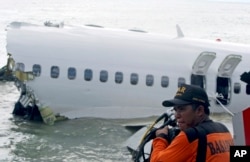 FILE - A rescue worker prepare to retrieve a Lion Air jet plane’s cockpit voice recorder out of the wreckage of the plane near the Ngurah Rai International airport in Kuta, Bali, Indonesia on Monday, April 15, 2013. (AP Photo/Firdia Lisnawati)