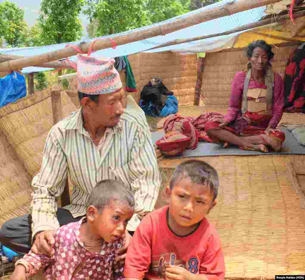 Seorang anak laki-laki berusia tiga tahun (kiri) dan neneknya (belakang) dipindahkan dari puing-puing rumah mereka di Ratomatey dan menunggu perawatan untuk luka-luka mereka.