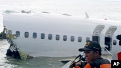 Un secouriste s’apprête à récupérer un enregistreur vocal dans les débris du poste de pilotage d’un avion de Lion Air près de l’aéroport international Ngurah Rai de Kuta, à Bali, en Indonésie, le 15 avril, 2013. (AP Photo/Firdia Lisnawati) 