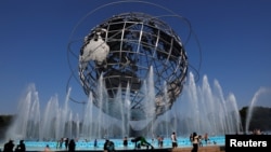 En esta gráfica del 2-7-18 el público busca combatir el calor en la fuente de la Unisphere, vestigio de la Feria Mundial de Nueva York 1964-1965, en Queens. REUTERS/Shannon Stapleton.