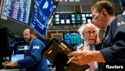 FILE - Traders work on the floor of the New York Stock Exchange (NYSE) in New York, March 29, 2018. With US stocks on a downhill slide, investors worry about President Donald Trump's attacks on giant online retailer Amazon and China's retaliatory impositi