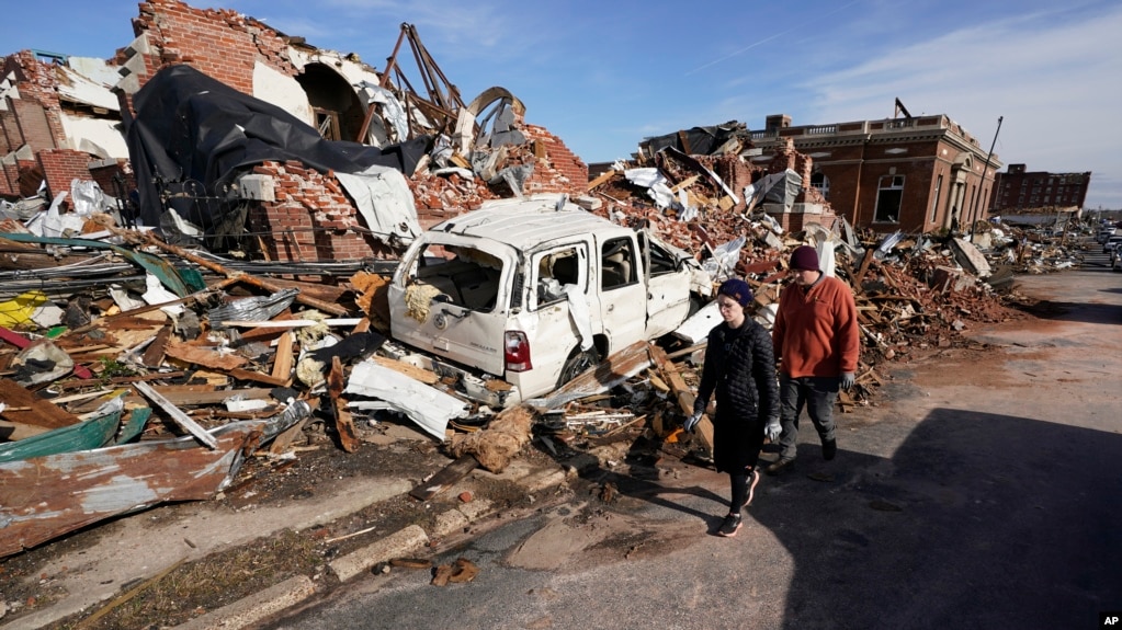 People survey damage from a tornado in Mayfield, Ky., on Saturday, Dec. 11, 2021. (AP Photo/Mark Humphrey)