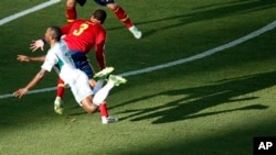 Nigeria's Sunday Mba, left, is airborne after colliding with Spain's Gerard Pique.