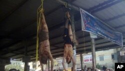 Egyptians surround the bodies of two men hung by their feet in a bus station after being accused of theft in the Nile Delta , about 90 kilometers north of Cairo, March 17, 2013. Egyptian vigilantes had beaten the two men, who they accused of stealing a motorized rickshaw, and who later died.