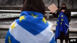 An anti-Brexit pro-Scottish independence activist wrapped in an EU flag holds a placard during a small protest against Britain's exit from the European Union outside the Scottish Parliament in Edinburgh on Dec. 31, 2020.