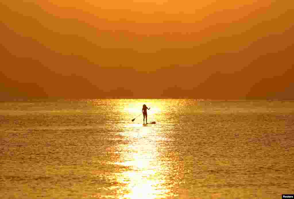 A woman paddles on a stand-up board during sunrise in a beach in Larnaca, Cyprus.