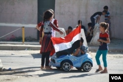 Children play with an Iraqi flag after Baghdad ordered troops were ordered to take Kirkuk from Kurdish forces on Oct. 17, 2017 in Kirkuk, Iraq. (H.Murdock/VOA)