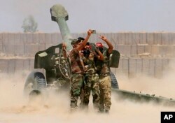 FILE - Fighters take a selfie while firing artillery against Islamic State militants in Fallujah, Iraq, May 29, 2016.