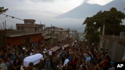 La gente lleva los ataúdes de siete personas que murieron durante la erupción del Volcán de Fuego, hacia el cementerio en San Juan Alotenango, Guatemala, el lunes, 4 de junio de 2018.