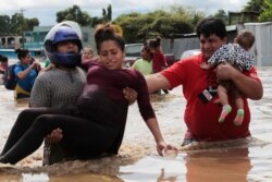 Una mujer embarazada es sacada de un área inundada por las lluvias del huracán Eta en Planeta, Honduras, el jueves 5 de noviembre de 2020.