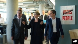 German Interior Minister Thomas de Maiziere; Eva- Maria Kirschsieper, Facebook head of public policy; and Martin Ott, Facebook managing director central Europe, from left, walk during a visit at the Facebook office in Berlin, Germany, Aug. 29, 2016. 