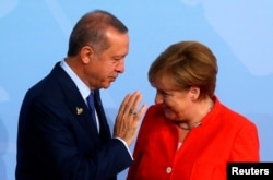 FILE - Turkish President Recep Tayyip Erdogan talks to German Chancellor Angela Merkel as he arrives for the G-20 leaders summit in Hamburg, Germany, July 7, 2017.