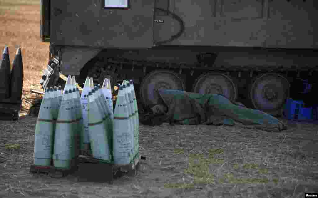 An Israeli soldier sleeps next to a mobile artillery unit outside the central Gaza Strip, July 10, 2014.