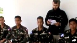 Foto yang diambil dari video ini menampilkan seorang pria (yang diduga anggota kelompok pemberontak Suriah) tengah membaca pernyataan terkait empat orang anggota pasukan perdamaian dari Filipina yang mereka sandera di Daraa, Suriah (9/5). (AP Photo/Ugarit News via AP video)