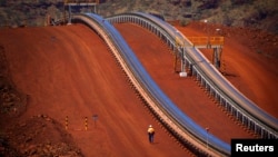 Một công nhân đi gần băng chuyền quặng tại mỏ sắt Fortescue Solomon, nằm trong Thung lũng Các Hoàng Đế, khoảng 400 km (248 dặm) về phía nam cảng Hedland, khu vực Pilbara, Tây Úc.