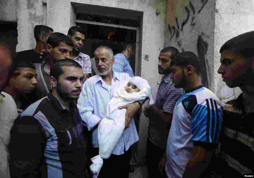 A relative of the wife of Hamas&#39;s military leader, Mohammed Deif, and his infant son Ali, whom medics said were killed in Israeli air strikes, carries Ali&#39;s body during the funeral, in the northern Gaza Strip, Aug. 20, 2014.