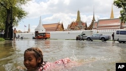 A girl swims in the floodwater in front of Bangkok's Grand Palace in a riverside neighborhood, Thailand.