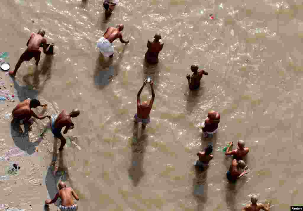 Hindu devotees pray in the waters of the river Ganga as they take a dip to honor the souls of their departed ancestors on Mahalaya, which is also called Shraadh or Pitru Paksha, in Allahabad, India.