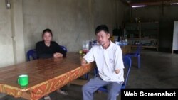 Houng Phomma Chak sit at a table with his daughter. In 2004, he lost both of his lower arms and was blinded in one eye when a bomb exploded while he was out collecting the old casings to sell for scrap metal.