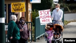 People wave signs at an intersection during a pre-planned rally against anti-Asian hate crimes held by the Asian American Pacific Islanders (AAPI) Organizing Coalition Against Hate and Bias in Newcastle, Washington, U.S. March 17, 2021. 