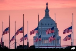 Flags flying a half-staff in honor of Sen. John McCain, R-Ariz., frame the U.S. Capital at daybreak in Washington, Aug. 26, 2018.