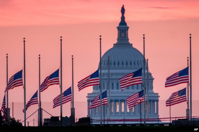 Flags flying a half-staff in honor of Sen. John McCain, R-Ariz., frame the U.S. Capital at daybreak in Washington, Aug. 26, 2018.