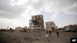 People stand by a building destroyed by a Saudi-led airstrike in Sana'a, Yemen, July 6, 2015. 