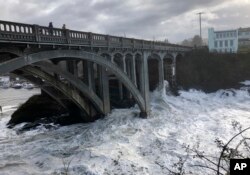In this Jan. 11, 2020 photo heavy surf surrounds the legs of a bridge as an extreme high tide rolls into the harbor in Depoe Bay, Oregon, USA. (AP Photo/Gillian Flaccus)