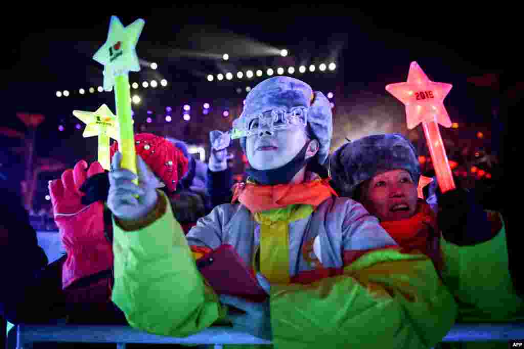 Warga menunggu untuk merayakan Tahun Baru dalam acara hitung mundur Malam Tahun Baru di dekat Stadion Nasional Beijing, yang dikenal sebagai Sarang Burung, di Beijing, China.