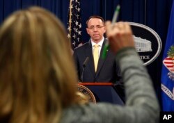 FILE - A reporter raises her hands to ask a question of Deputy Attorney General Rod Rosenstein, after he announced the office of special counsel Robert Mueller says a grand jury has charged 13 Russian nationals and several Russian entities, Feb. 16, 2018, in Washington.
